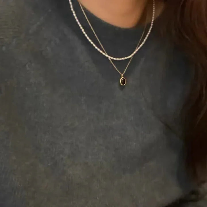 Damenhalskette mit schwarzem Anhänger und Perlenkette, eleganter Schmuck, Nahaufnahme.