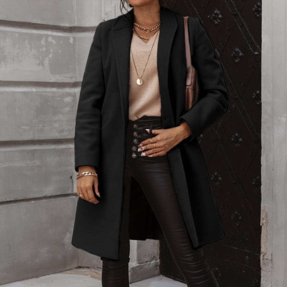 Frau in schwarzem Wollmantel, Lederhose, beige Pullover, Goldschmuck, modisch, elegant.
