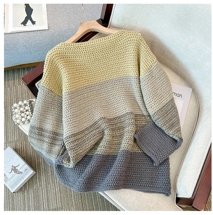 Gestrickter Pullover Damen, mehrfarbig, beige-grau, gemütlich, Herbstmode, auf Sofa drapiert.