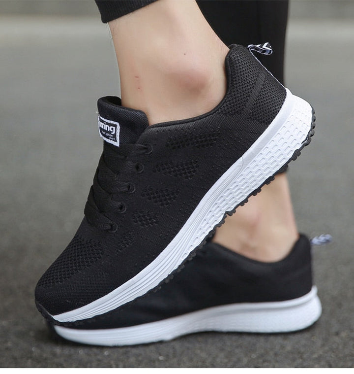 Schwarze Sportschuhe mit weißer Sohle, atmungsaktives Mesh, ideal für Laufen und Fitness.