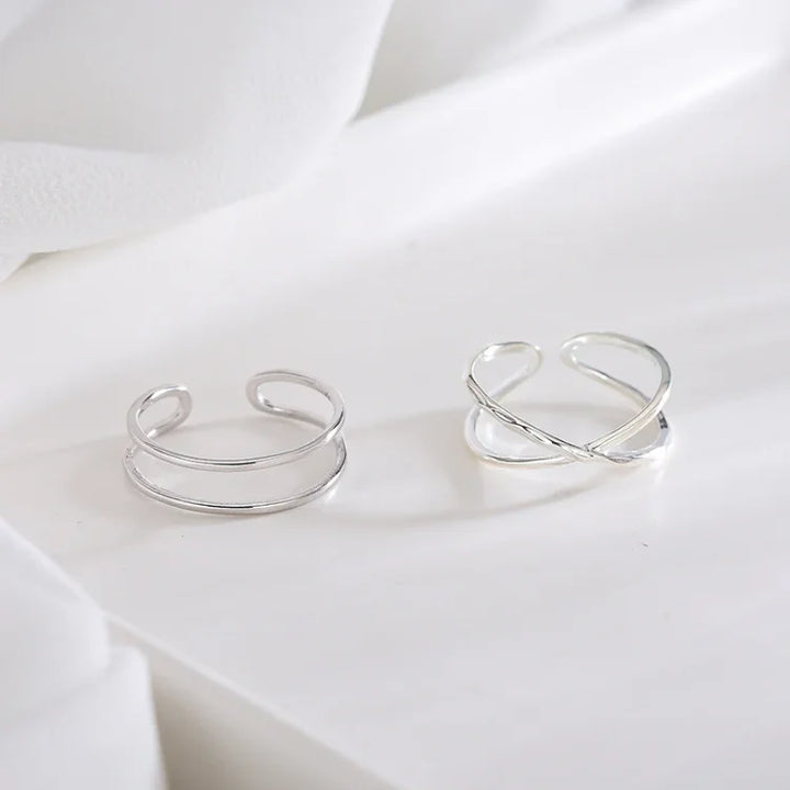 Zwei silberne offene Ringe auf weißem Hintergrund, minimalistisches Schmuckdesign.
