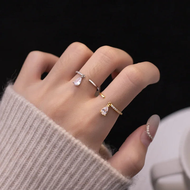 Hand mit drei eleganten Ringen, Tropfenform, Silber und Gold, Damenmode, Schmucktrends.