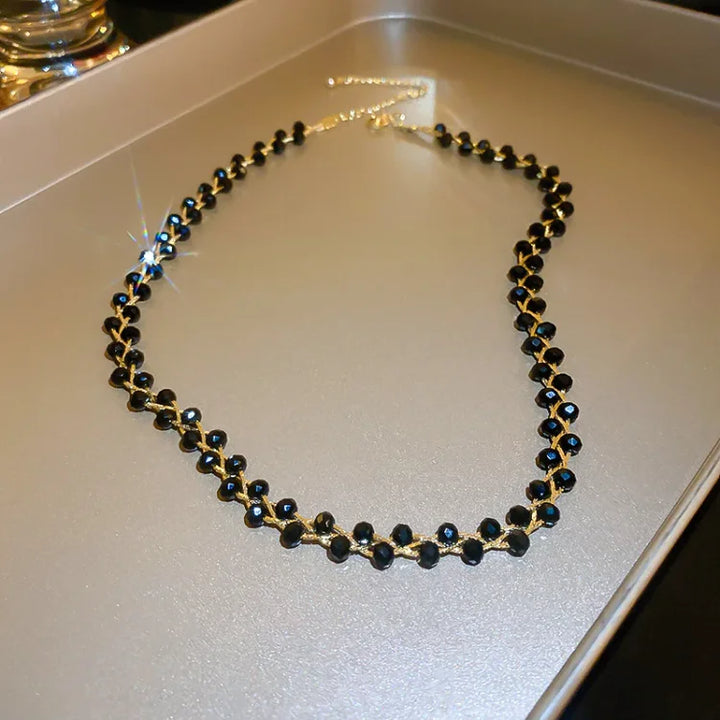 Goldene Halskette mit schwarzen Perlen, elegantes Schmuckstück, modisches Accessoire.