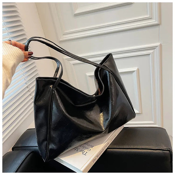 Schwarze Lederhandtasche auf Sofa, elegantes Design, Damenmode, Accessoire, stilvoll.