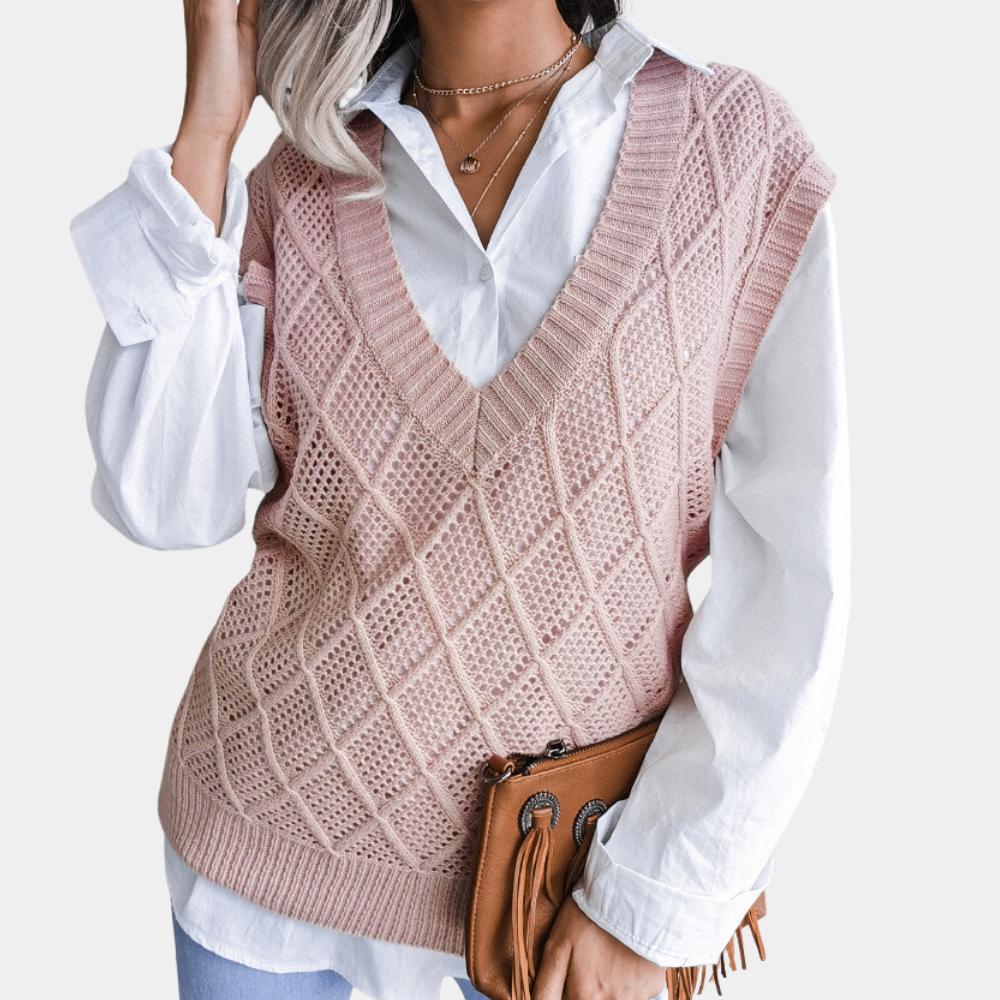 Frau in rosa Strickweste über weißer Bluse, hält braune Lederhandtasche, modisch, elegant.