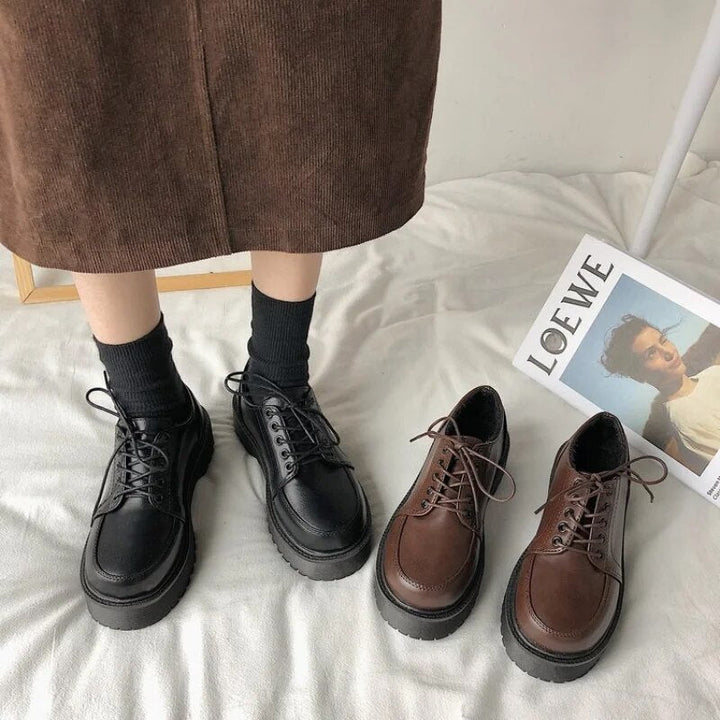 Schwarze und braune Schnürschuhe aus Leder auf Teppich neben Zeitschrift.