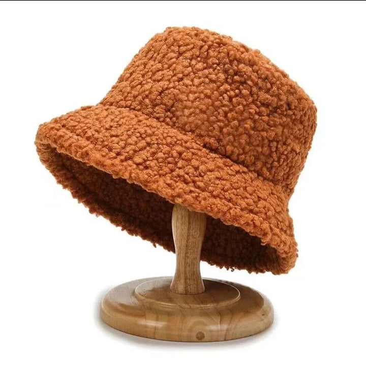 Brauner Teddyfell-Bucket-Hut auf Holzständer, modisch, warm, Winteraccessoire.