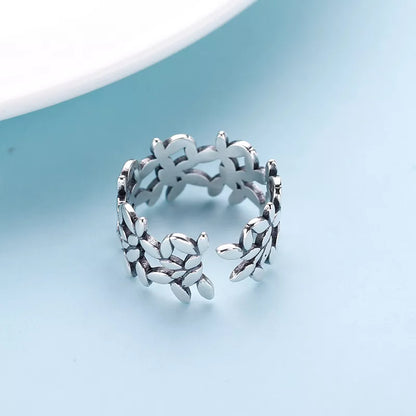 Silberner verstellbarer Damenring mit Blumenmuster auf blauem Hintergrund.