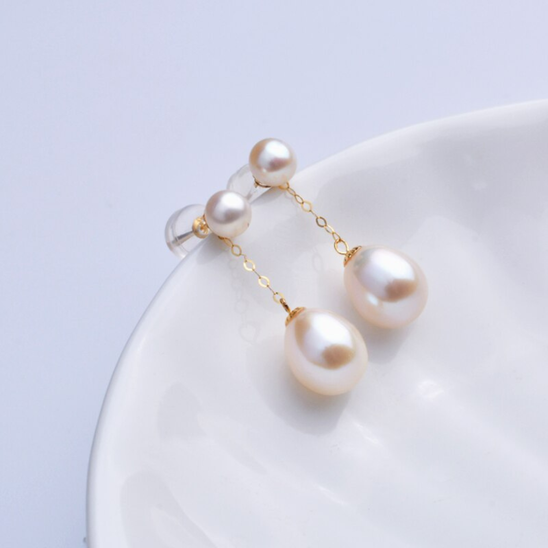 Perlenohrringe mit goldener Kette, Tropfenform, eleganter Schmuck, weißer Hintergrund