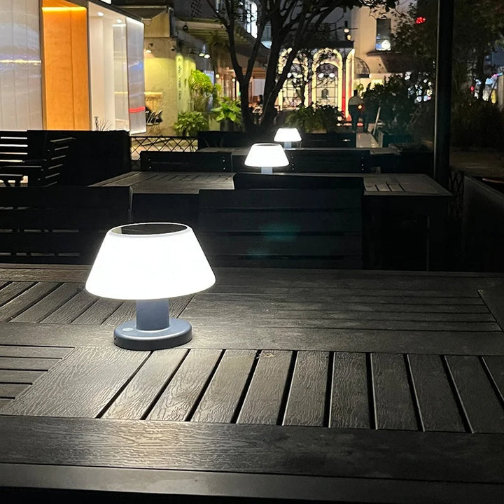 Moderne LED-Tischlampe auf dunklem Holztisch im Freien bei Nacht, stilvolle Beleuchtung.