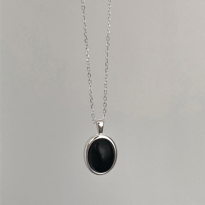 Silberkette mit schwarzem ovalem Anhänger, eleganter Schmuck, minimalistisches Design.