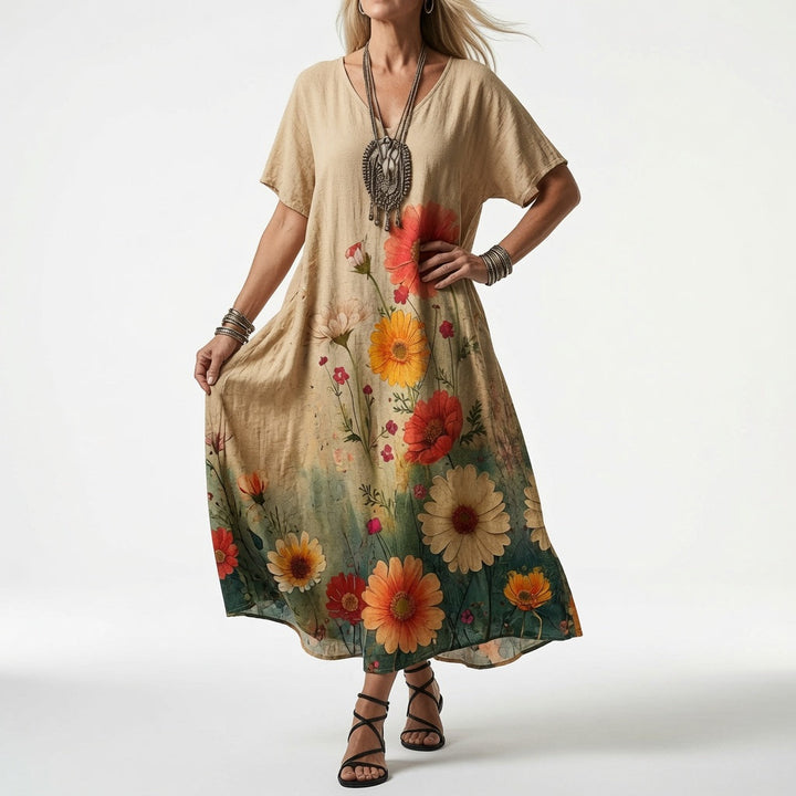 Modelka v béžových šatech s velkými oranžovými a červenými květy u spodního lemu, zelený přechod, doplňky ve stylu boho. 3