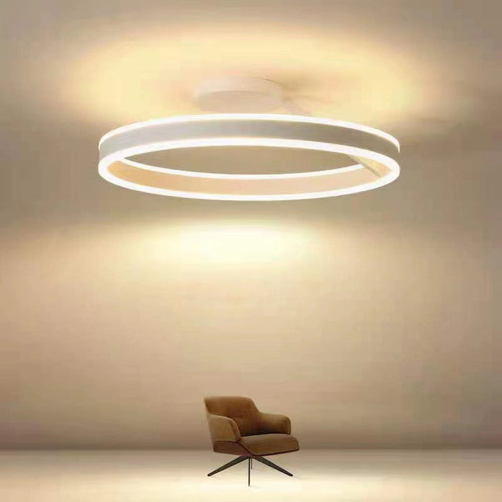 Moderne LED-Deckenleuchte, rund, weiß, energiesparend, über braunem Sessel im Wohnzimmer.