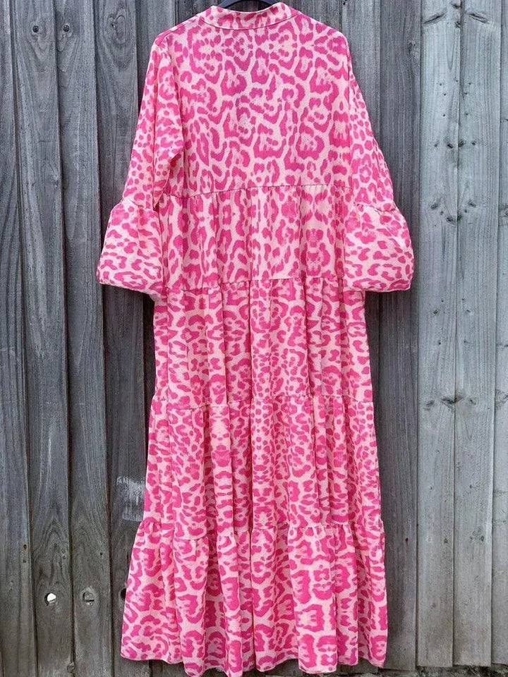 Rosa Maxikleid mit Leopardenmuster, langärmelig, aus Baumwolle, vor Holzwand.