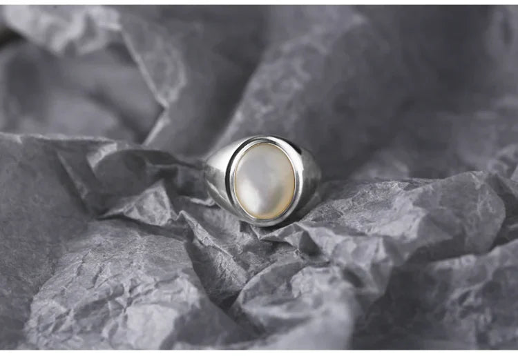 Silberring mit Perlmuttstein auf grauem Hintergrund, eleganter Schmuck für Damen.