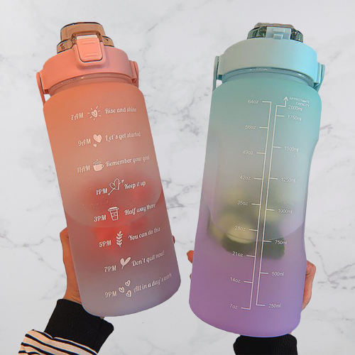 Zwei bunte Wasserflaschen mit Zeitmarkierungen, rosa und blau, aus Kunststoff, auf Marmorhintergrund.