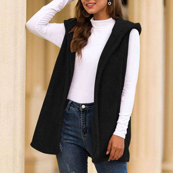 Frau trägt schwarze ärmellose Weste, weiße Langarmbluse, blaue Jeans, modisch, elegant.