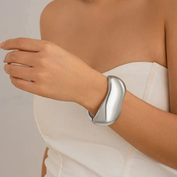 Futuristisches silbernes Armband, minimalistisches Design, getragen von Frau in weißem Kleid.