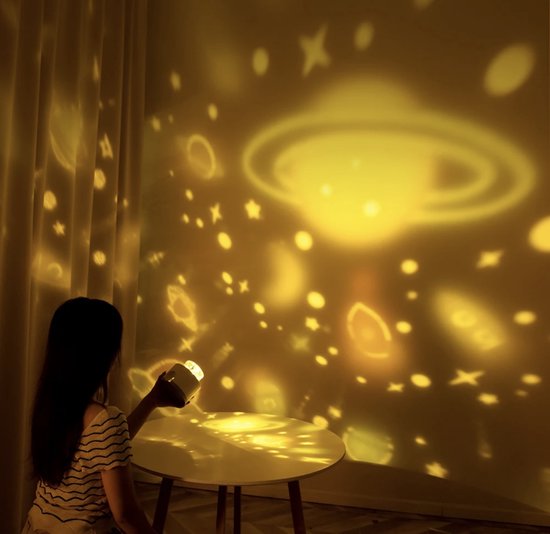 Frau mit Projektor, projiziert Planeten und Sterne an Wand, gelbes Licht, stimmungsvolle Beleuchtung.