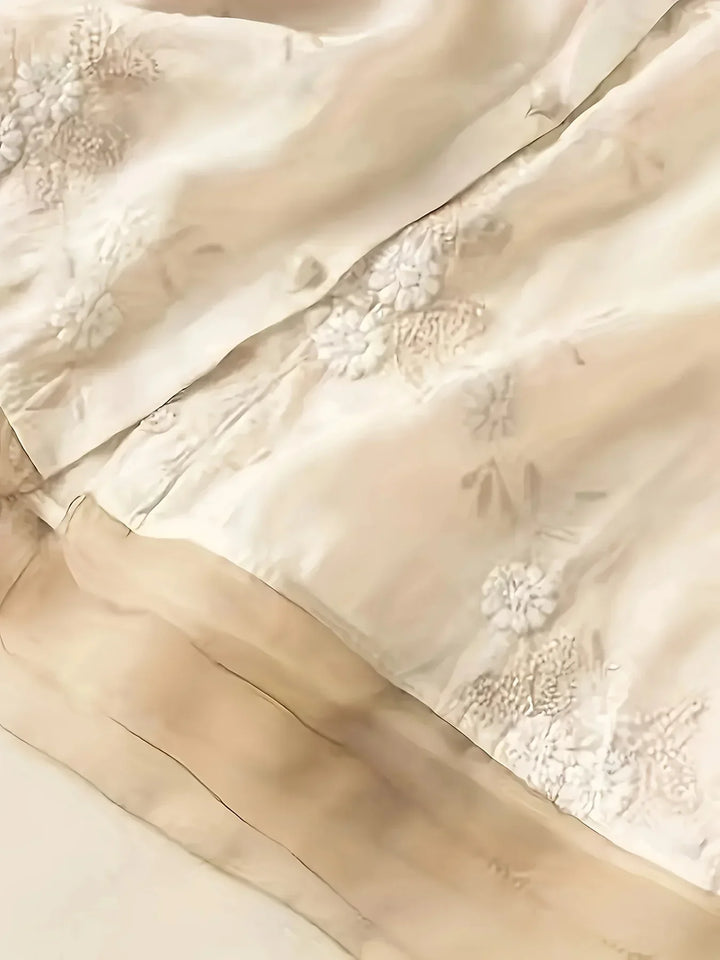 Beige Seidenstoff mit floraler Stickerei, luxuriöses Material für elegante Mode und Dekoration.