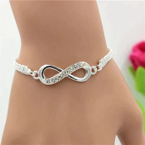 Silbernes Unendlichkeitsarmband mit Strasssteinen auf Handgelenk, eleganter Schmuck für Damen.