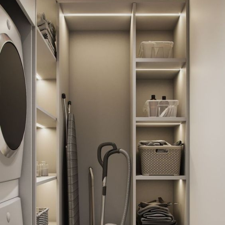 Moderner Hauswirtschaftsraum mit Stauraum, Regalen, Staubsauger und Wäschekorb in neutralen Farben.