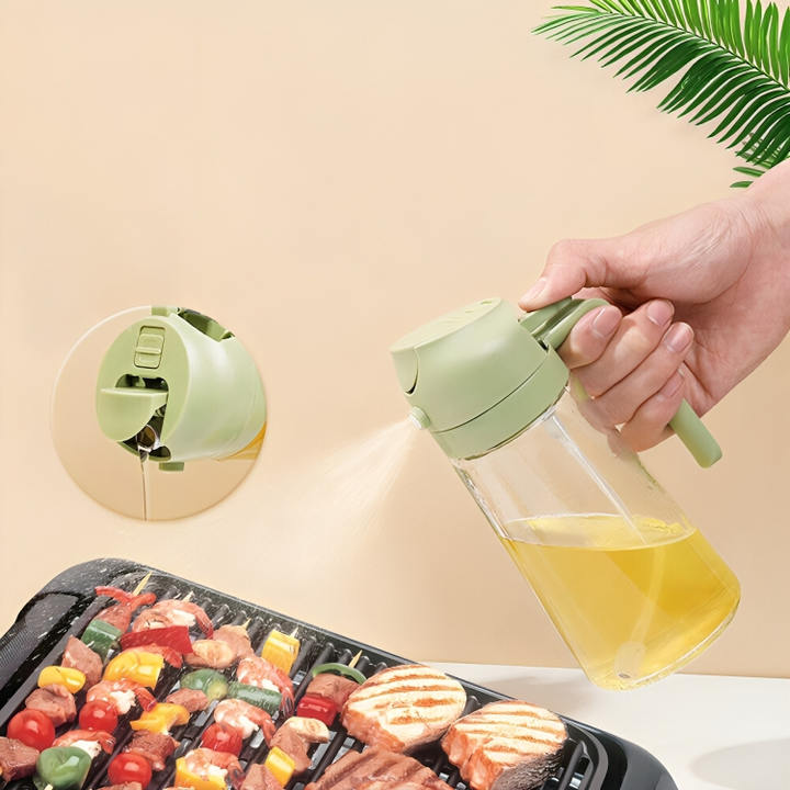 Grüne Ölsprühflasche aus Glas, handgehalten, beim Grillen von Fleisch und Gemüse.