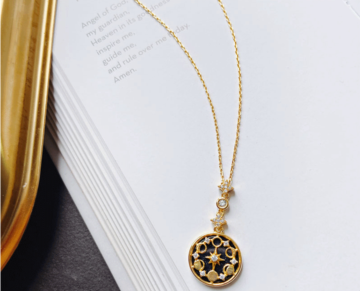Goldene Halskette mit rundem Anhänger auf Buch, elegantes Schmuckdesign, Damenaccessoire.