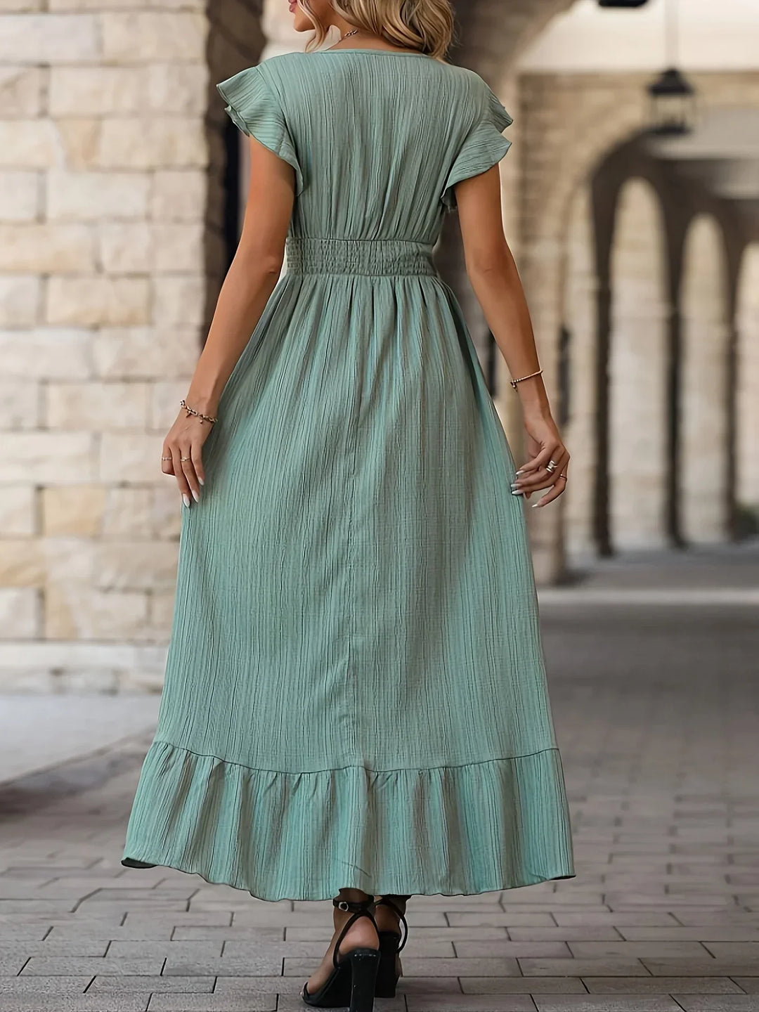 Frau in langem, grünem Sommerkleid aus Baumwolle, Rückansicht, elegantes Design, Stadtumgebung.