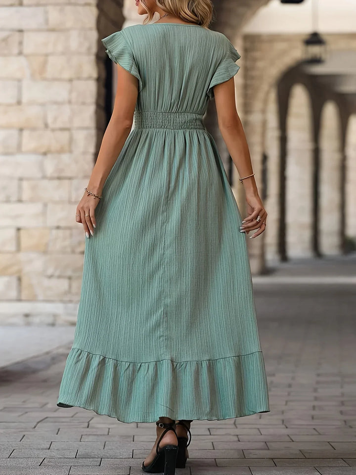 Frau in langem, grünem Sommerkleid aus Baumwolle, Rückansicht, elegantes Design, Stadtumgebung.