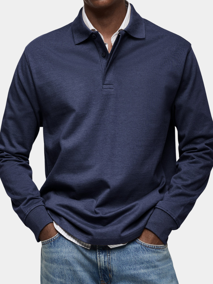 Tmavě modré polo tričko s dlouhým rukávem na modelovi, zblízka na límec, knoflíky a žebrované manžety, s rukama v kapsách džín. 1