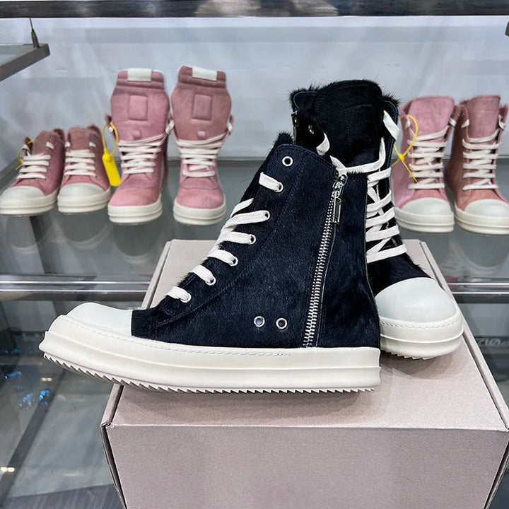 Schwarze High-Top-Sneaker mit Reißverschluss, Leder, Unisex, vor rosa Schuhen im Hintergrund.