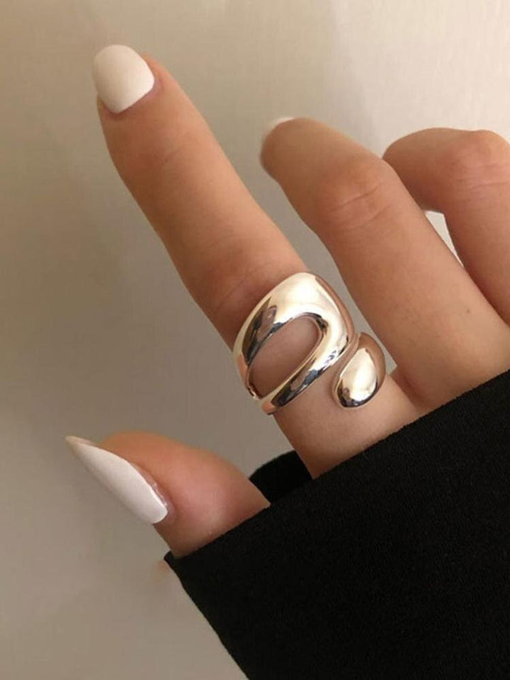 Silberner Statement-Ring, modern, glänzend, an Finger getragen, minimalistisches Design.