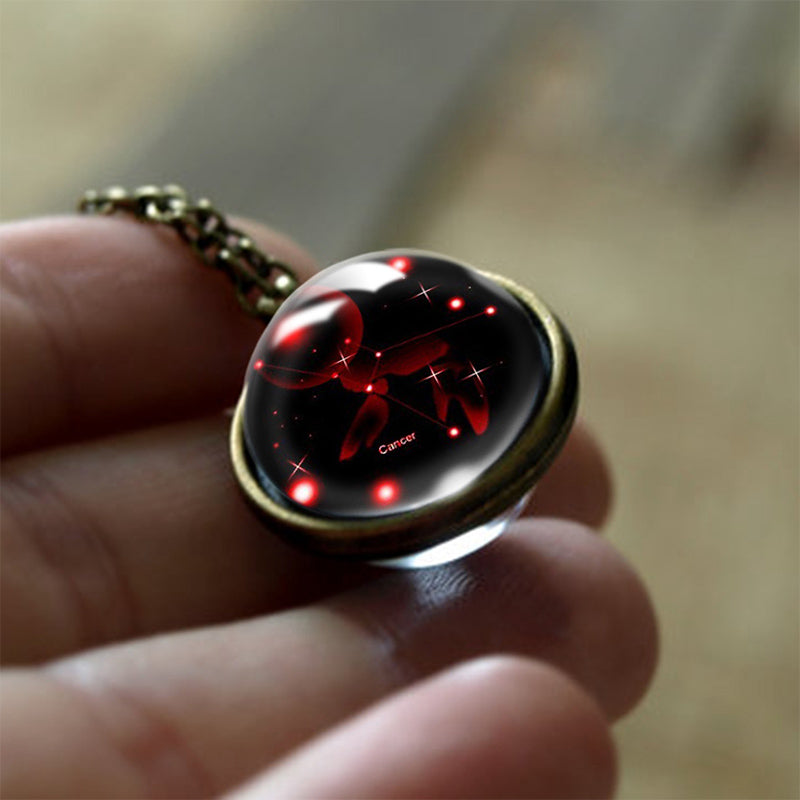 Krebs Sternzeichen Anhänger, rund, Glas, rot-schwarz, astrologisches Schmuckstück, Hand gehalten.