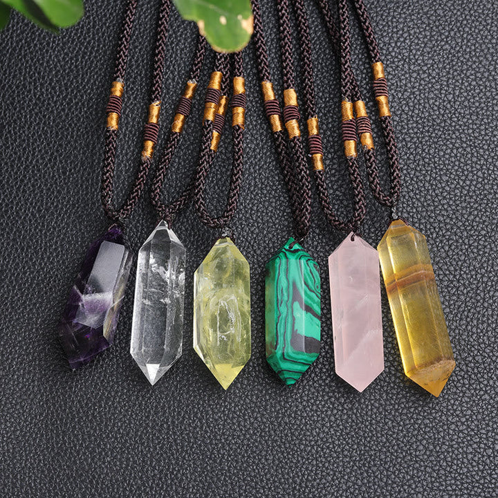 Verschiedene Kristallanhänger auf schwarzem Hintergrund, Amethyst, Quarz, Malachit, Rosenquarz.