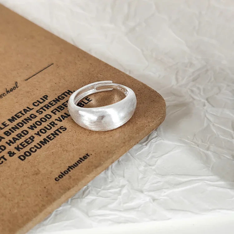 Silberner Ring auf braunem Karton, minimalistisches Design, Schmuck, Modeaccessoire.