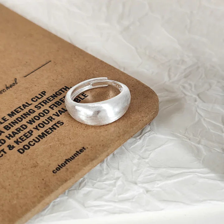Silberner Ring auf braunem Karton, minimalistisches Design, Schmuck, Modeaccessoire.