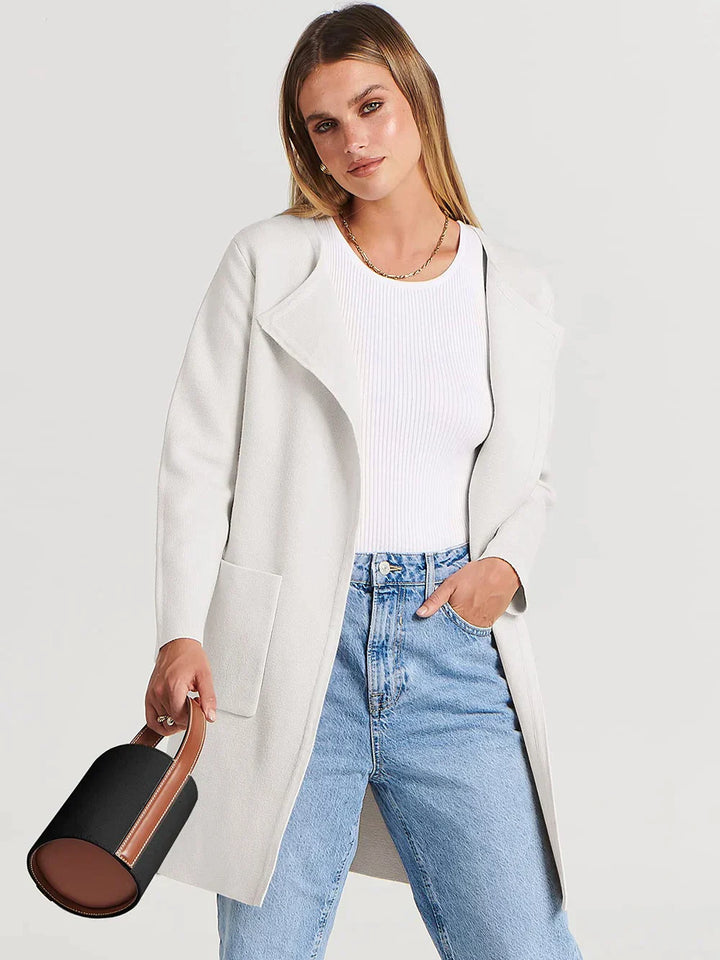 Frau in weißem Mantel, blauer Jeans, weißem Top, hält schwarze Handtasche, Mode, Damenbekleidung.