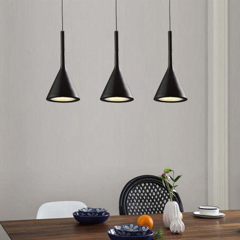 Drei schwarze Pendelleuchten über Esstisch, modernes Design, minimalistische Inneneinrichtung.