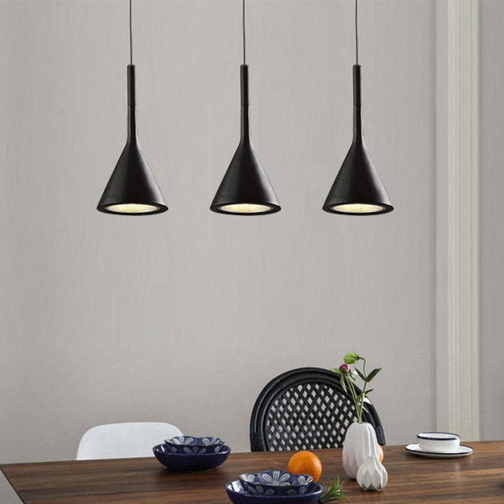 Drei schwarze Pendelleuchten über Esstisch, modernes Design, minimalistische Inneneinrichtung.