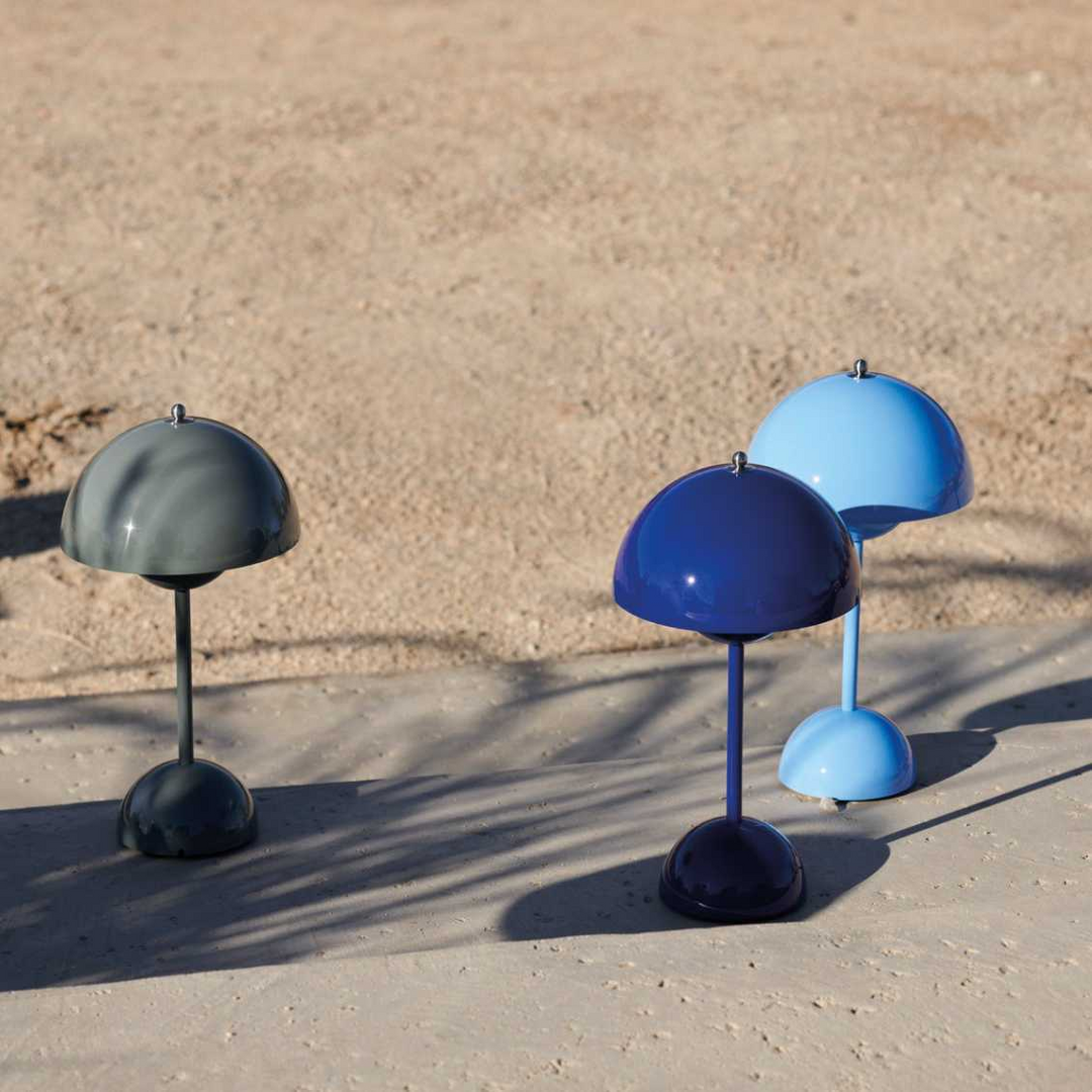 Drei bunte Tischlampen im Freien auf Sand, moderne Designleuchten, blau und grau.