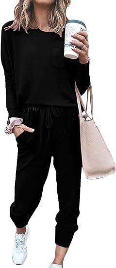 Frau in schwarzem Freizeitanzug mit Kaffeebecher und beiger Tasche, lässige Mode.