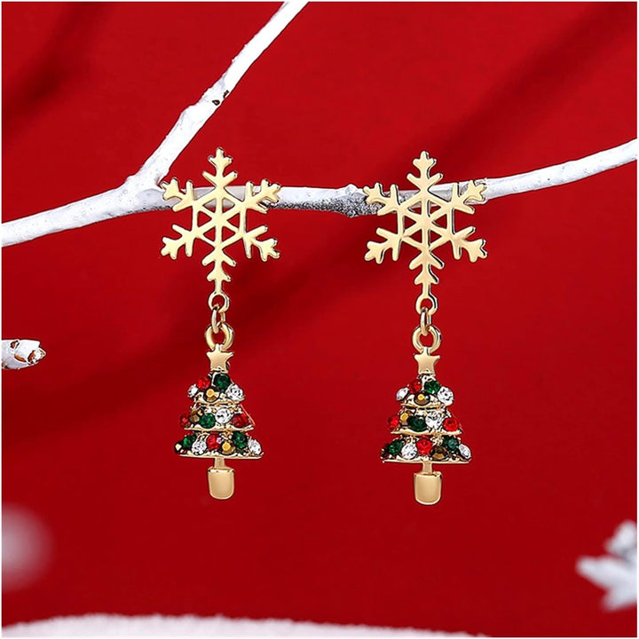 Goldene Schneeflocken-Ohrringe mit buntem Weihnachtsbaum-Anhänger auf rotem Hintergrund.
