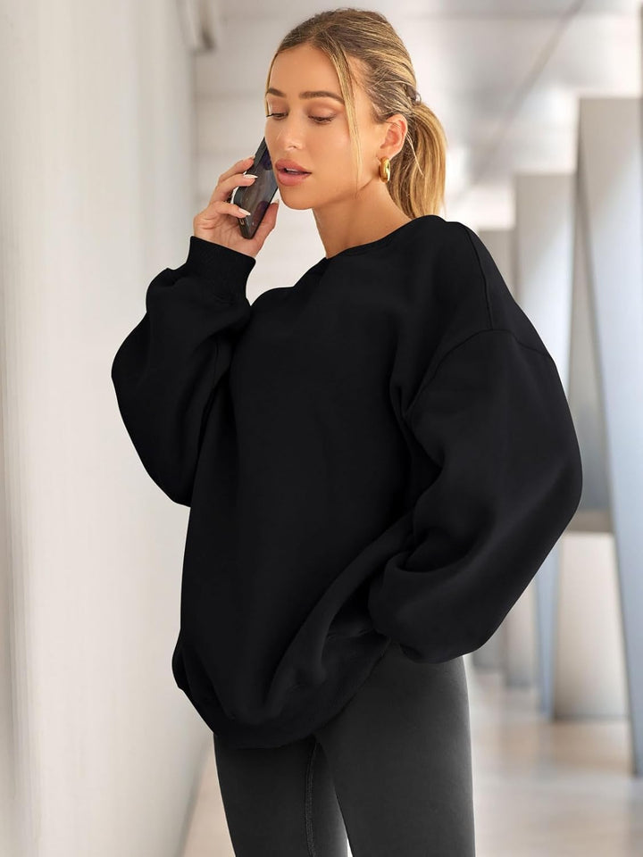 Frau in schwarzem Oversize-Pullover telefoniert, modisch, lässig, Herbstmode, Innenraum.