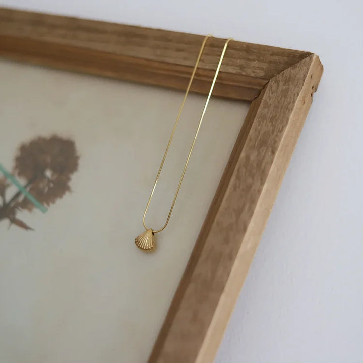 Goldene Muschelkette auf Holzrahmen, minimalistischer Schmuck, elegantes Design, Damenaccessoire.