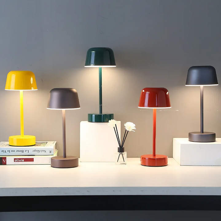 Moderne Tischlampen in Gelb, Braun, Grün, Rot und Grau auf weißem Tisch, LED-Beleuchtung.