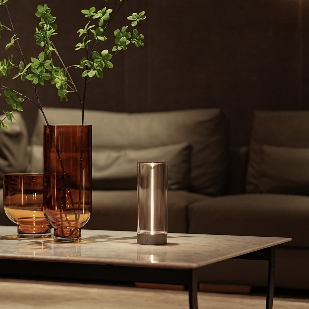 Moderne Tischlampe aus Metall auf Marmortisch, neben braunen Glasvasen, Wohnzimmer-Dekor.
