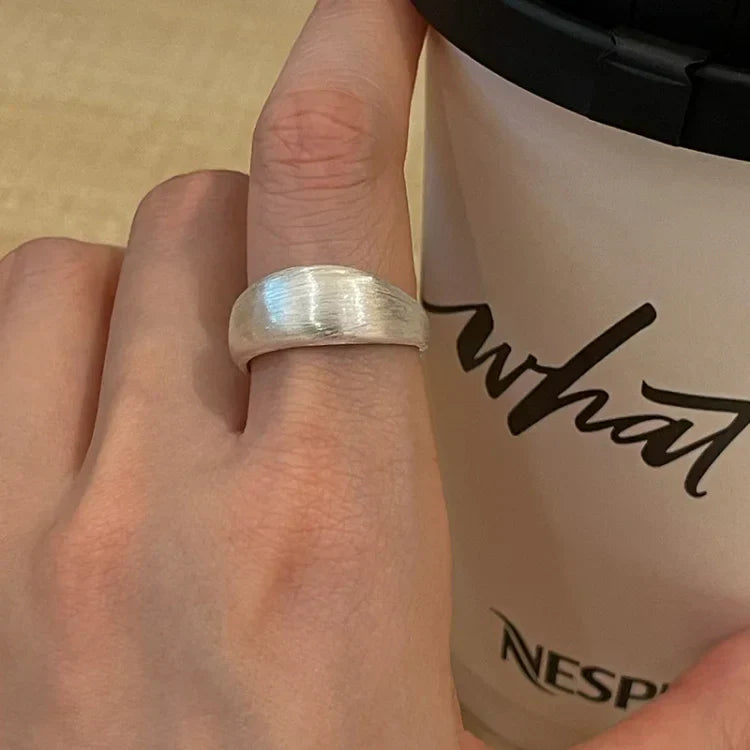 Silberner Ring auf Hand, neben Nespresso-Becher, minimalistisches Schmuckdesign.