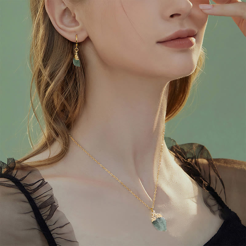 Frau mit goldener Halskette und Ohrringen, grüner Edelstein, eleganter Schmuck, Nahaufnahme.