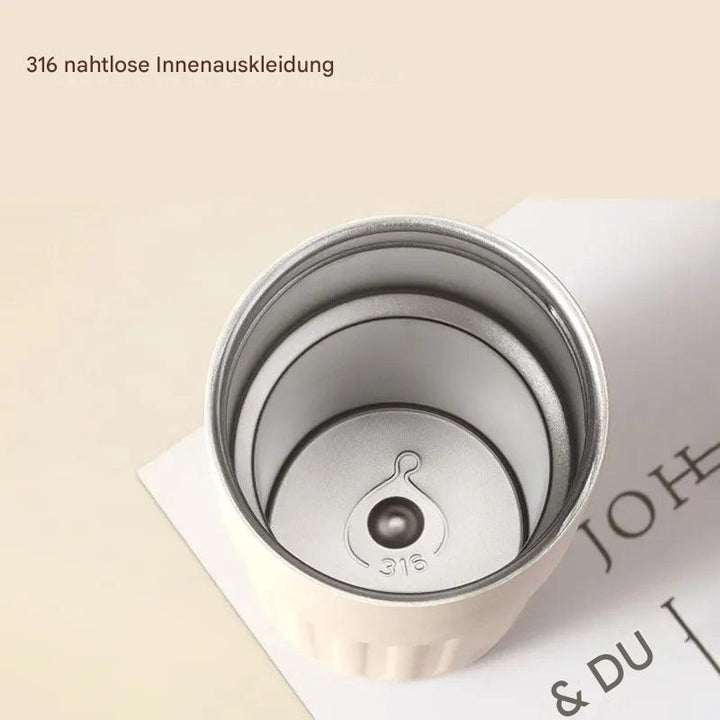 Weißer Thermobecher aus Edelstahl 316, nahtlose Innenauskleidung, auf Buch liegend.